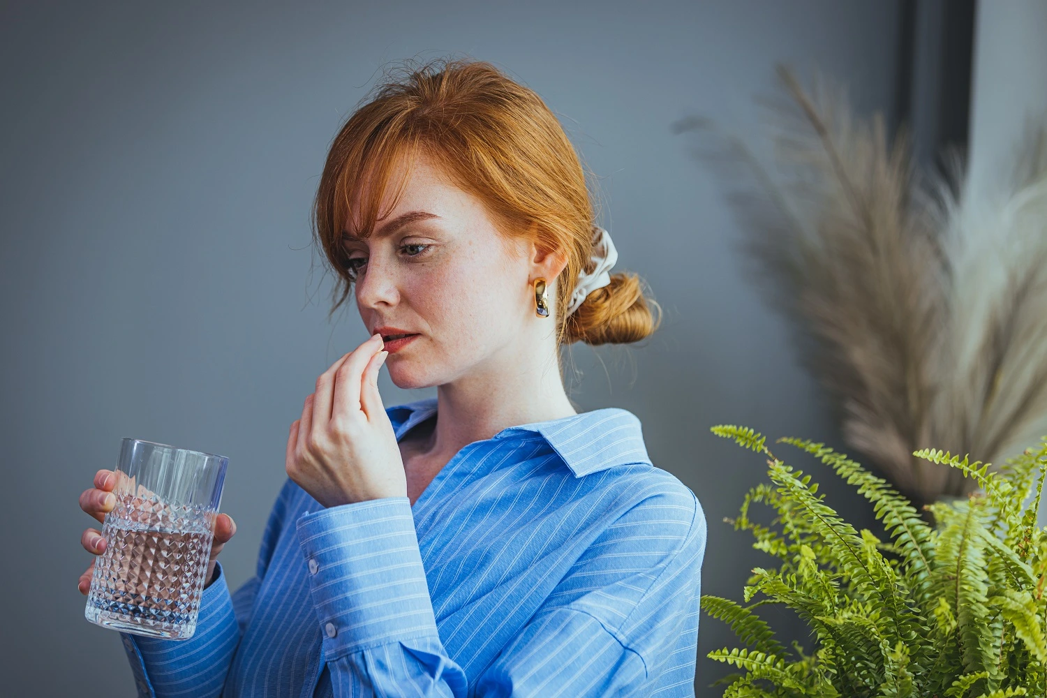 Woman taking daily supplements with water