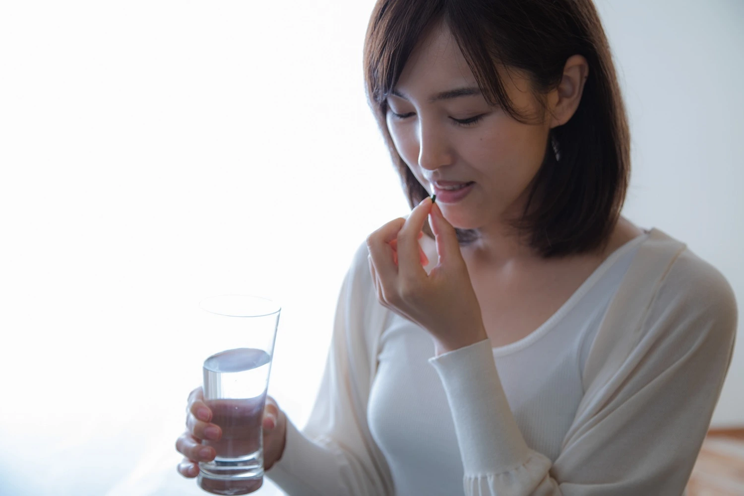 Woman taking a chlorella tablet as part of her daily wellness routine