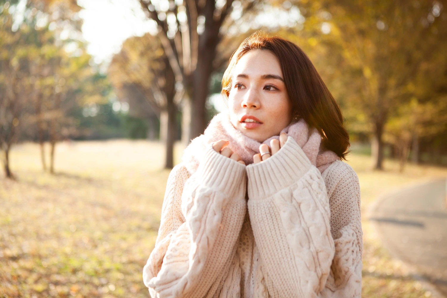Woman walkng through a park during a seasonal transition, representing sustained vitality and wellness consistency.